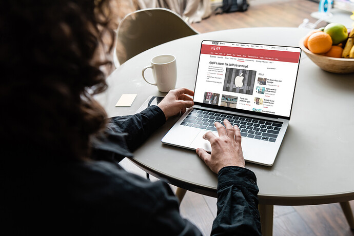 Rückenansicht eines Lesers, der einen Laptop mit BBC-Nachrichten und Apple-Logo auf dem Bildschirm