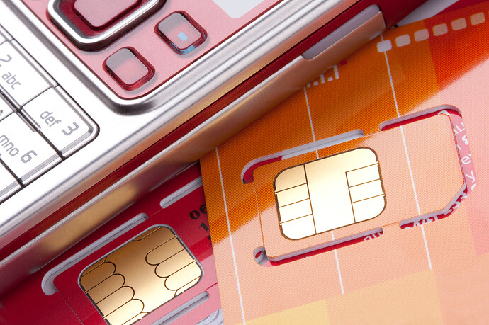 Vor einem Mobiltelefon liegen SIM-Karten verschiedener Mobilfunkanbieter