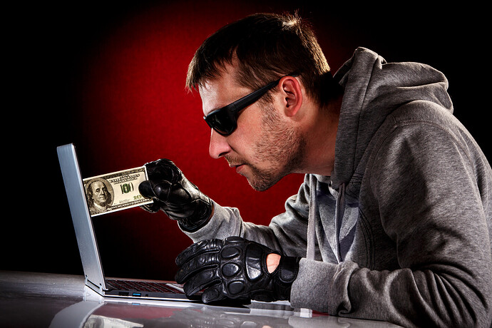Hacker zieht einen Geldschein aus seinem Notebook