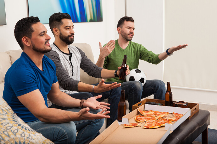 Drei Fußballfreunde schauen sich ein Spiel an und essen Pizza