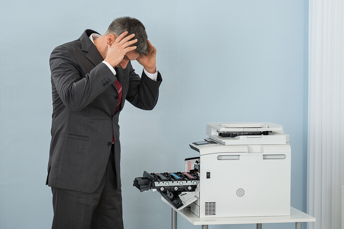 Geschäftsmann schaut verzweifelt auf seinen Drucker