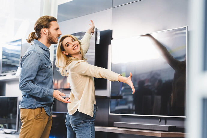 Junges Paar bewundert einen großen Fernseher