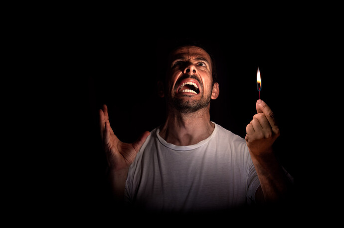 Ein verärgerter Mann schaut mit einem Streichholz in der Dunkelheit nach oben