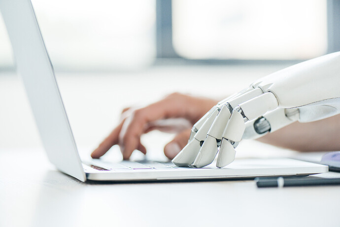 Eine menschliche Hand neben der eines Roboters auf einem Notebook
