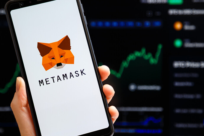 Smartphone mit MetaMask-Logo und Krypto-Kursverlauf im Hintergrund