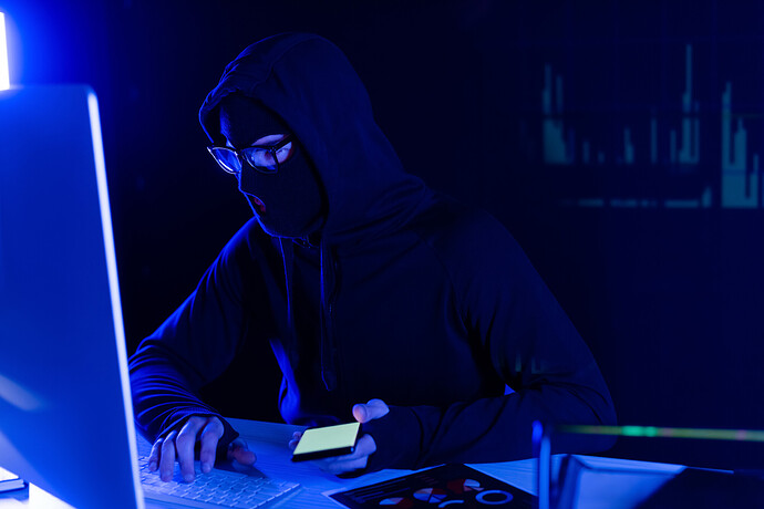 Maskierter Hacker mit einem Smartphone in der Hand