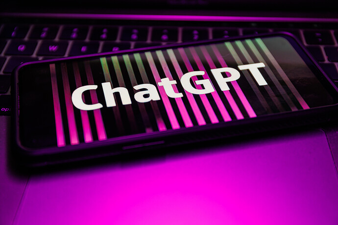 Ein Smartphone mit dem Schriftzug "ChatGPT" liegt auf einem Laptop