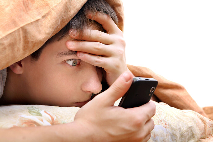 Ein Jugendlicher schaut ungläubig auf sein Handy