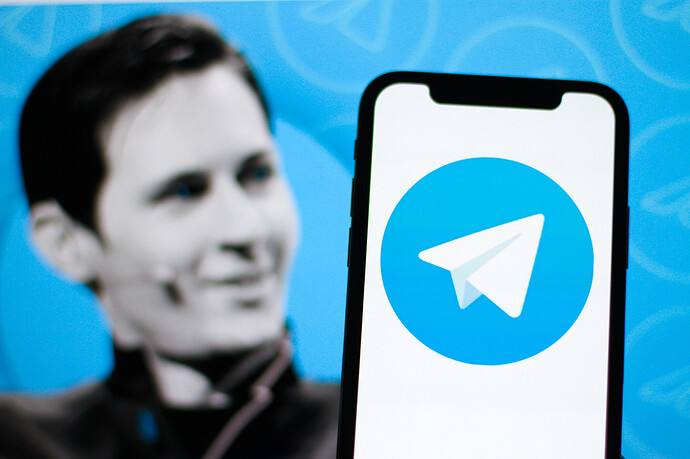 Das Logo von Telegram auf einem Smartphone. Im Hintergrund der Gründer von Telegram. Pavel Durov