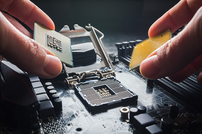 Eine Hand hält zwei CPUs vor ein Mainboard