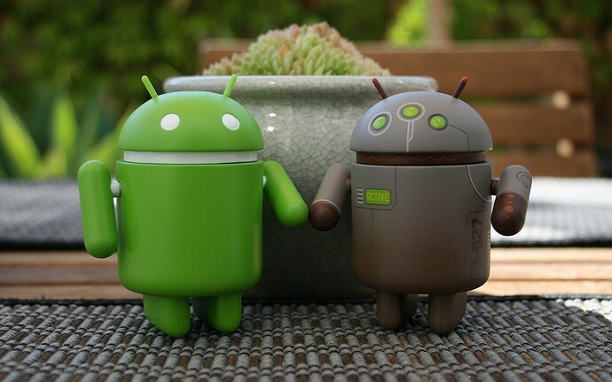 Zwei Android-Figuren vor einer Pflanze.