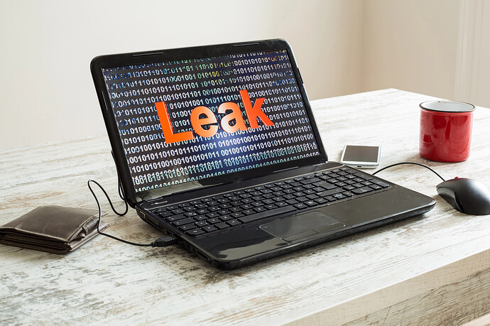 Ein Laptop steht auf einem Tisch und zeigt das Wort "Leak" vor Binärcode