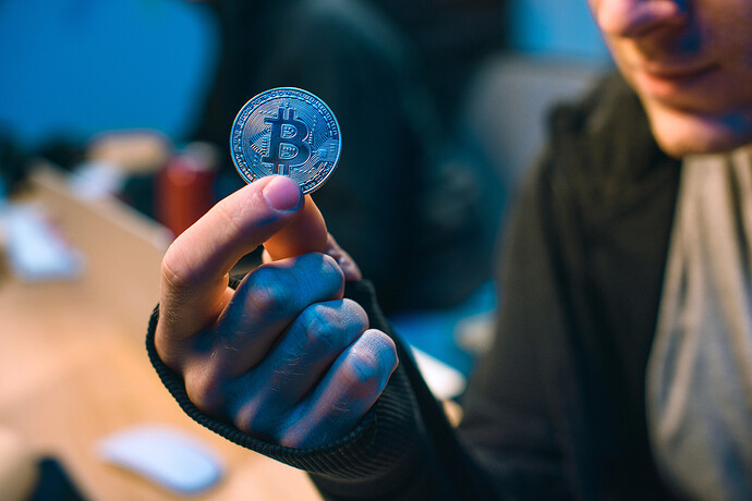 Ein Mann hält eine Bitcoin-Münze in der Hand