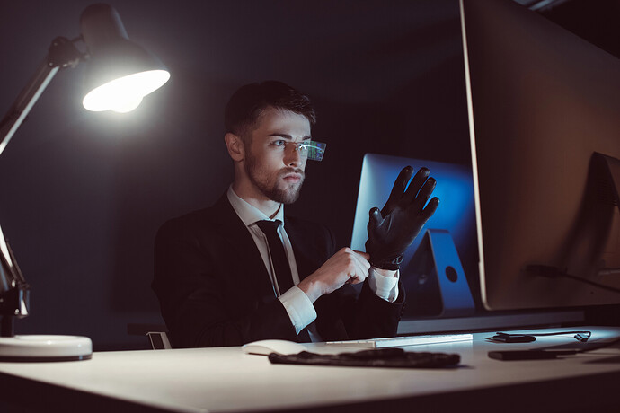 Porträt eines Ermittlers, der Handschuhe trägt und auf einen Computerbildschirm auf einem Schreibtisch blickt