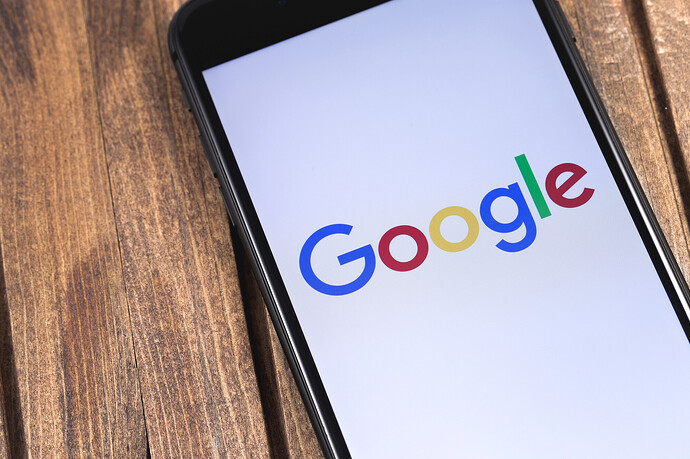 Auf einem Holztisch liegt ein Smartphone mit Google-Logo