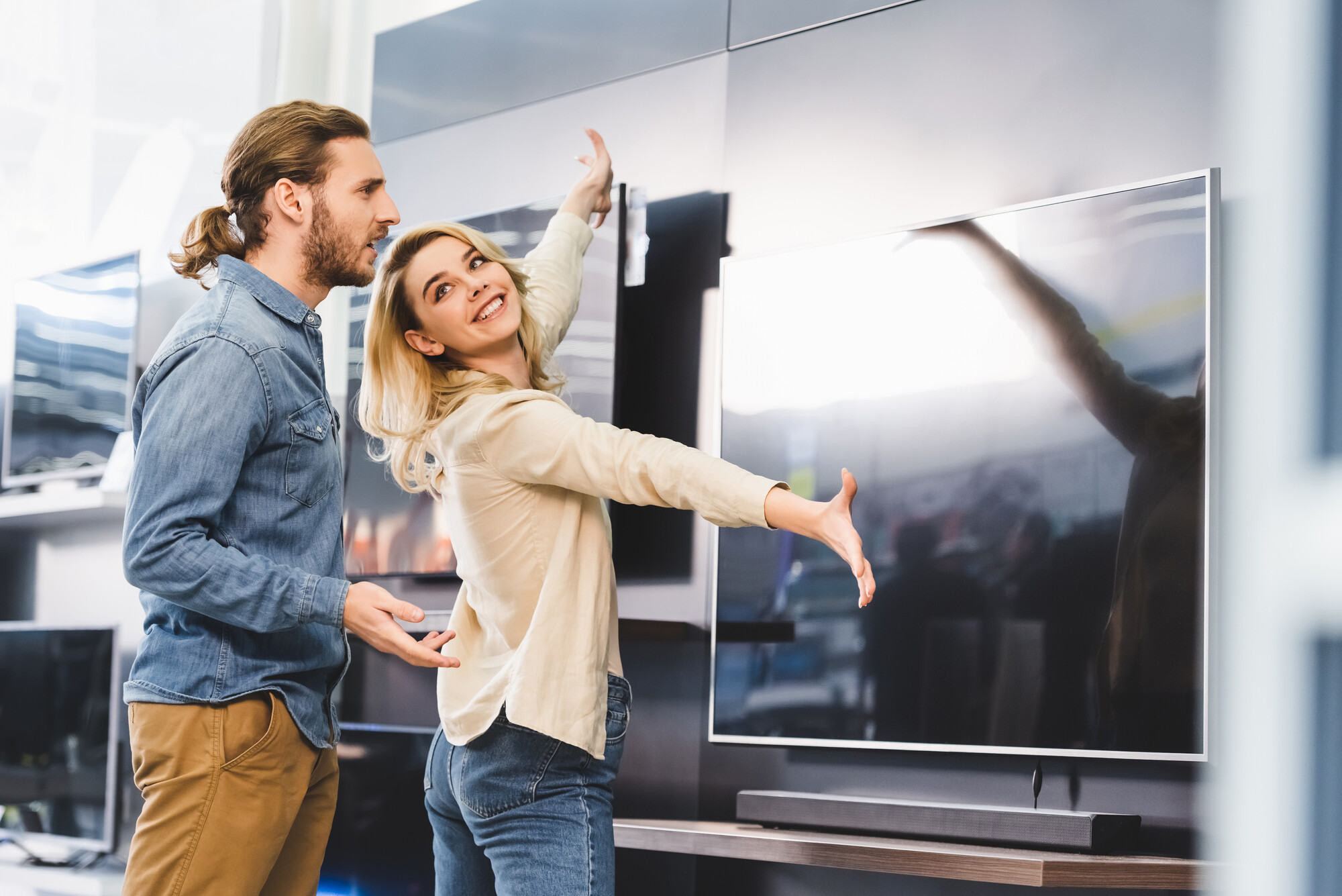 Junges Paar bewundert einen großen Fernseher