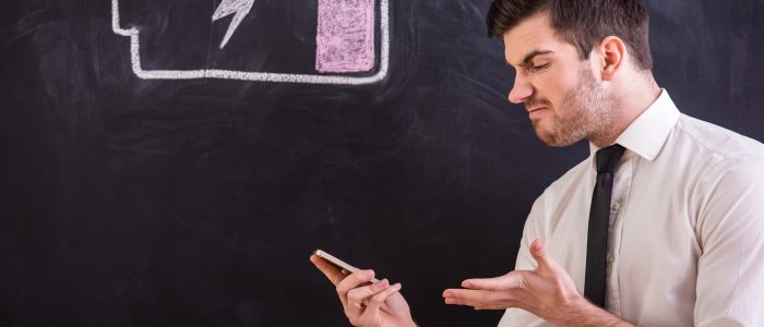 Mann schaut auf sein Smartphone mit fest verbautem und schon wieder leerem Akku (Symbolbild)