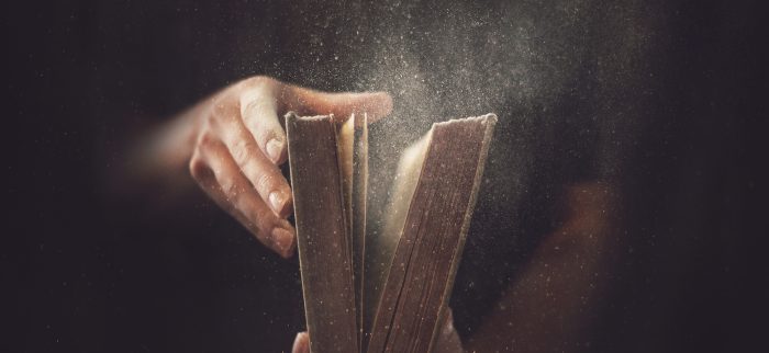 Zwei Hände halten ein altes staubiges Buch