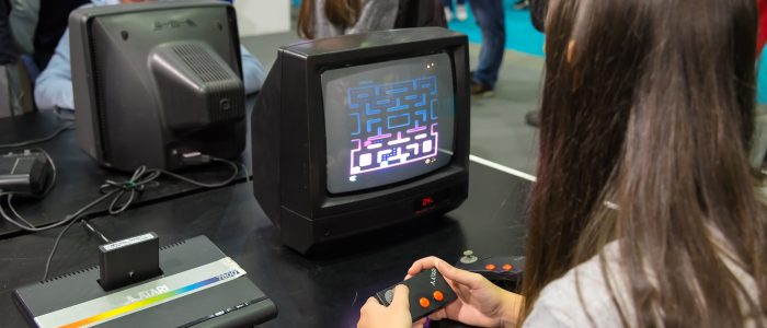 Junge Frau spielt auf einer alten Atari-Spielekonsole