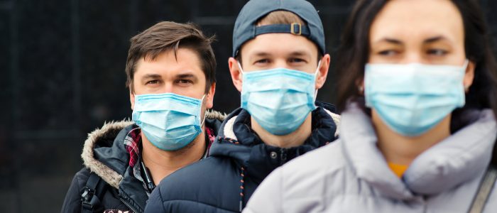 Drei Personen tragen Atemschutzmasken, um ihre Mitmenschen vor Covid-19 zu schützen