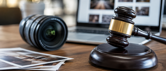 Richterhammer neben Kameraobjektiv und Fotografien als Symbolbild für Bildrechte, Nutzungsrechte und die Haftung von Händlern bei fremden Werbefotos.