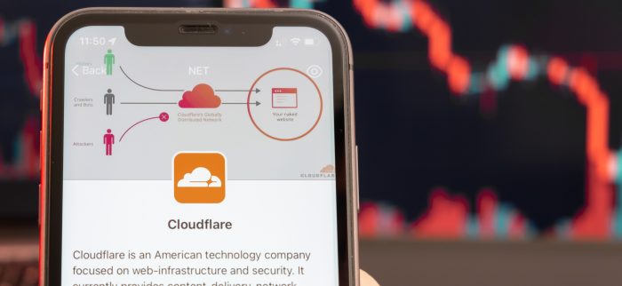 Smartphone mit einer Cloudflare-Anwendung und einem fallenden Aktienkurs im Hintergrund