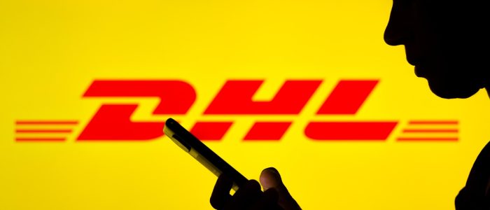 Schatten eines Mannes, der auf sein Smartphone schaut, im Hintergrund das DHL Logo