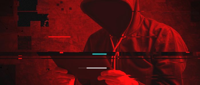 Vermummter Hacker mit Tablet in der Hand