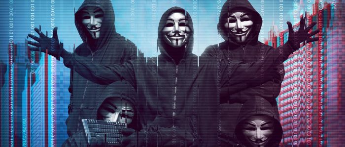 Gruppe von Hackern mit Anonymous-Maske vor Binärcode im Hintergrund