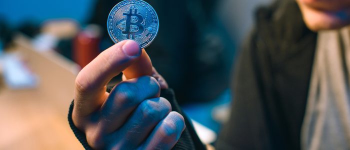 Ein Mann hält eine Bitcoin-Münze in der Hand