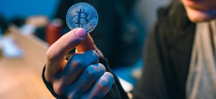 Ein Mann hält eine Bitcoin-Münze in der Hand