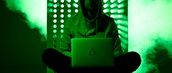 Getöntes Bild von einem Hacker im Kapuzenpulli mit Laptop