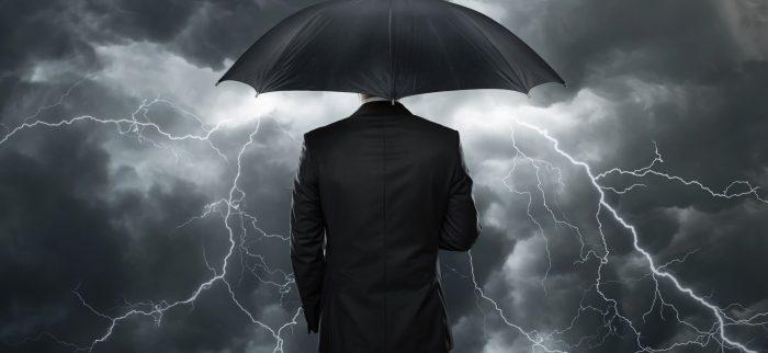 Geschäftsmann mit Regenschirm vor einem Unwetter stehend