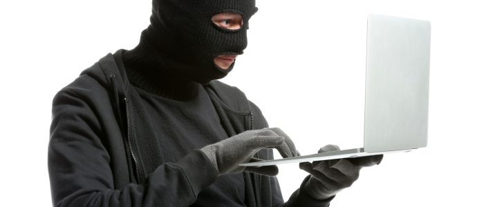 Ein männlicher Hacker mit Maske und einem Laptop