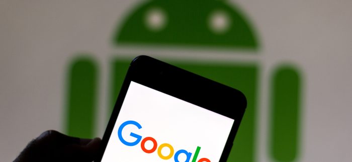 Das Google-Logo wird auf einem Smartphone angezeigt. Im Hintergrund ist das Android-Logo zu sehen