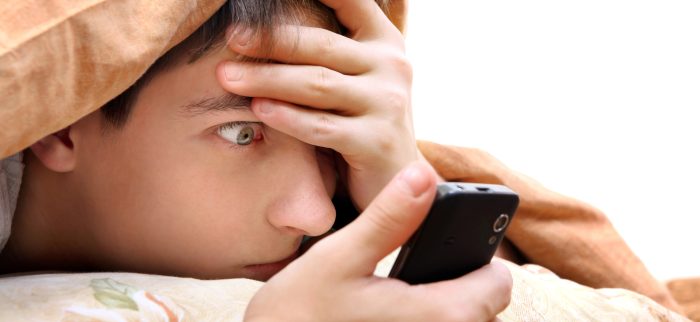 Ein Jugendlicher schaut ungläubig auf sein Handy