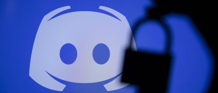 Unscharfes Smartphone vor dem Discord-Logo auf blauem Hintergrund als Symbolbild fuer die KI-gestuetzte Altersverifizierung und Verhaltensanalyse auf Discord.