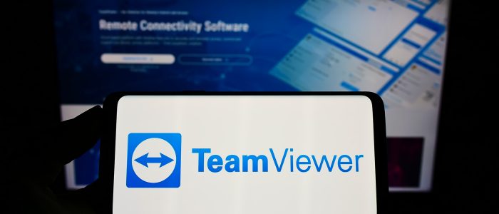 TeamViewer-Logo auf Handybildschirm mit Webseite im Hintergrund