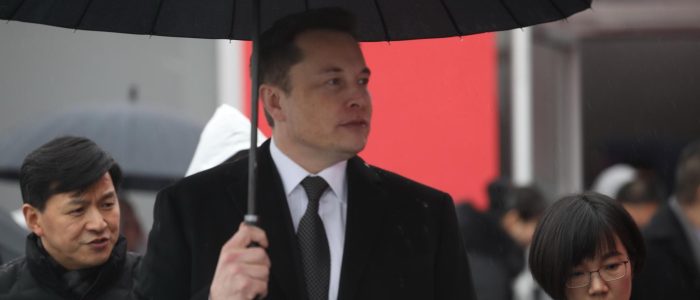 Elon Musk mit einem schwarzen Regenschirm