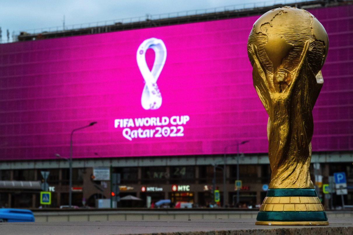 Ein Pokal steht vor einem Werbebanner der Fußball WM 2022