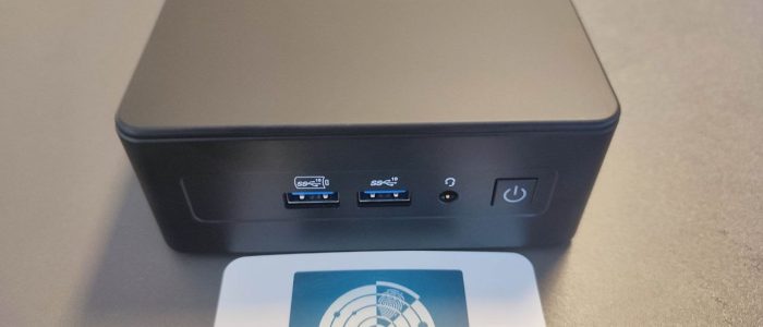 Der GEEKOM IT15 steht auf einem Tisch. Im Vordergrund eine Visitenkarte von Tarnkappe.info.