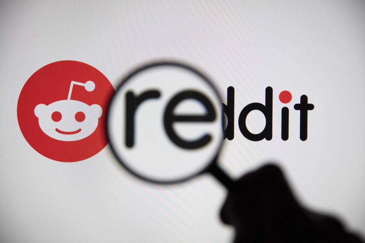 Eine Lupe vor einem Reddit-Logo