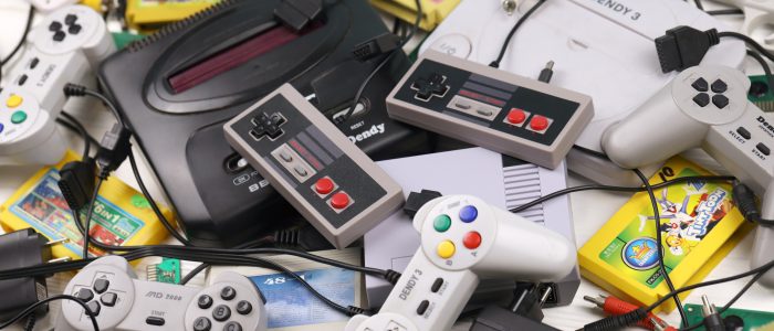 Mehrere Retrogaming-Konsolen mit Controllern auf einem Haufen