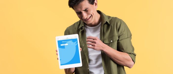 Trauriger Mann hält ein Tablet mit Twitter-App in seiner Hand