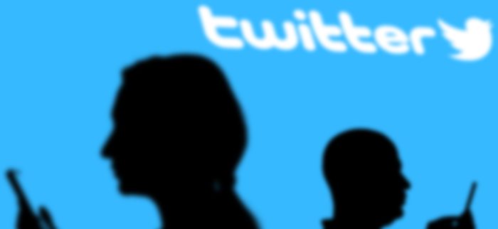 Schatten zweier Smartphone-Nutzer mit Twitter-Logo im Hintergrund