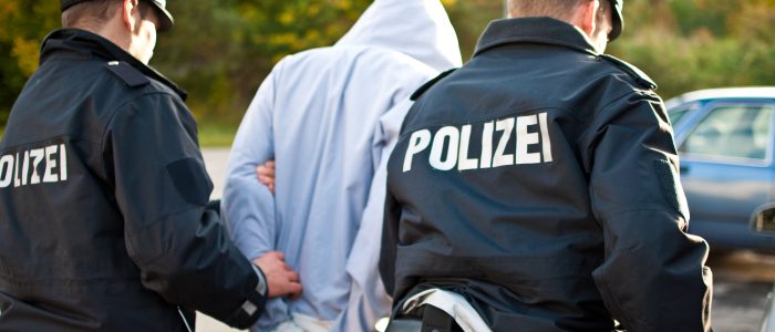 Zwei Polizisten führen einen Tatverdächtigen ab