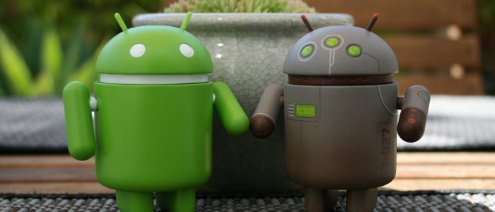 Zwei Android-Figuren vor einer Pflanze.