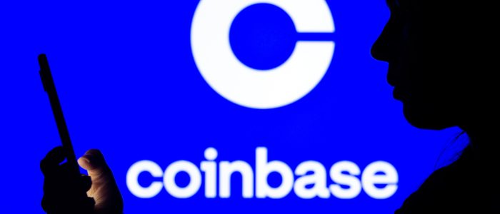 Schatten einer Person, die auf ihr Smartphone schaut mit Coinbase-Logo im Hintergrund