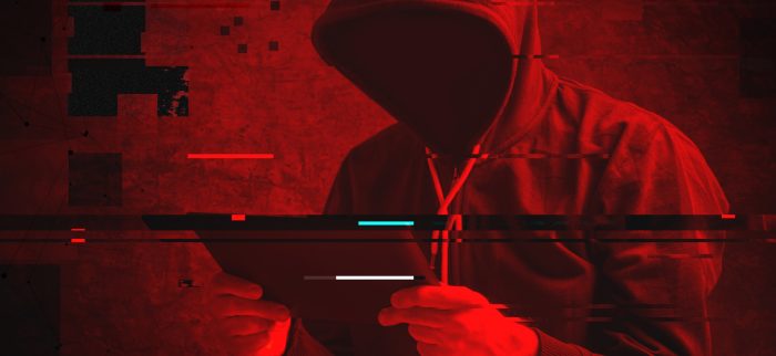 Vermummter Hacker mit Tablet in der Hand