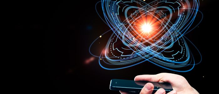 Eine Hand hält ein Smartphone mit einem abstrakten digitalen Atom